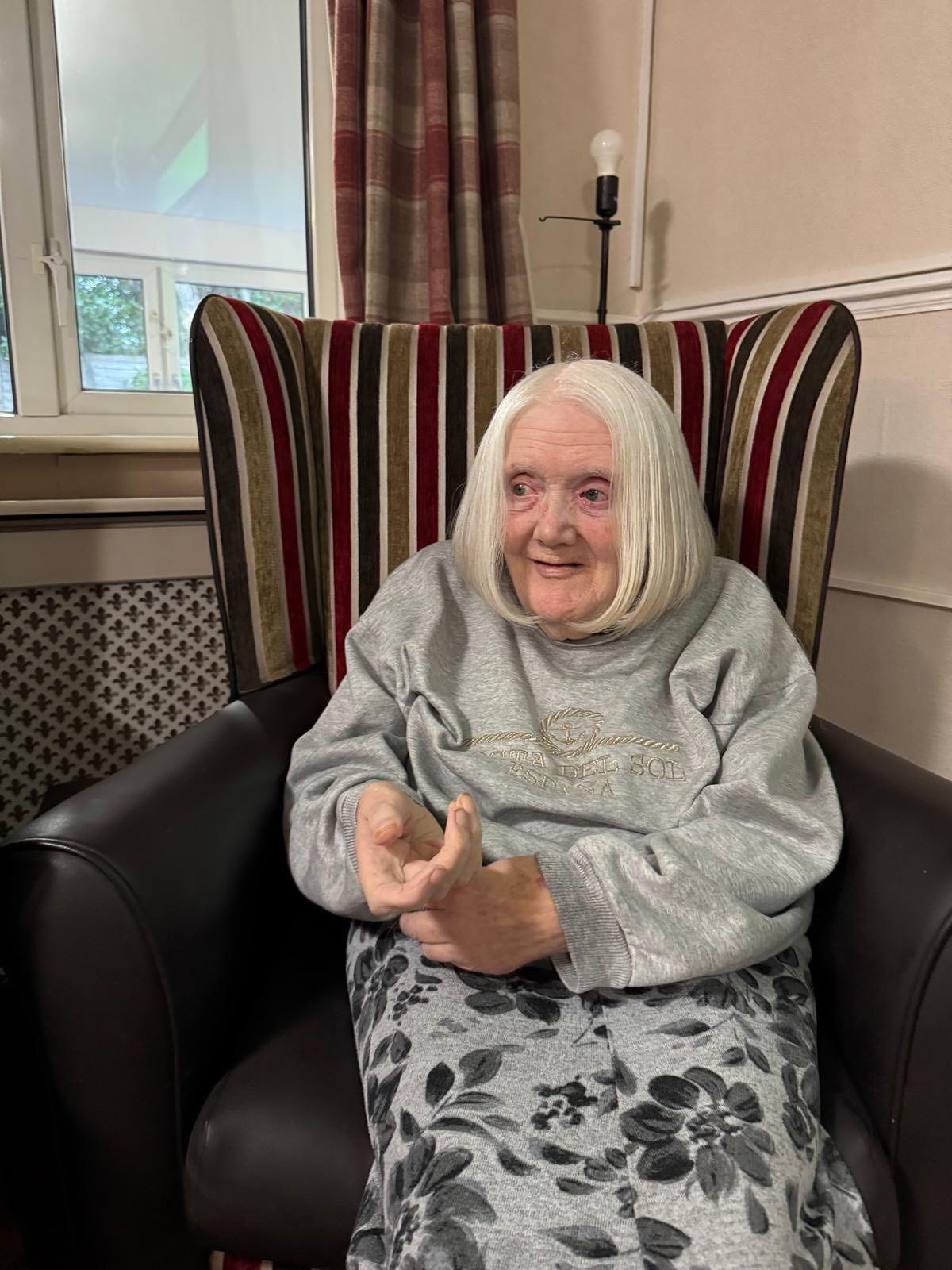 Elderly woman seated comfortably indoors