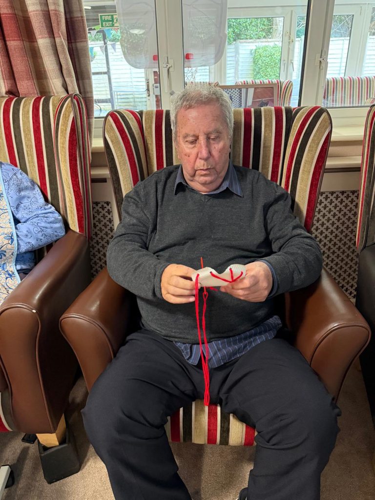 Resident seated comfortably while threading yarn through a craft activity