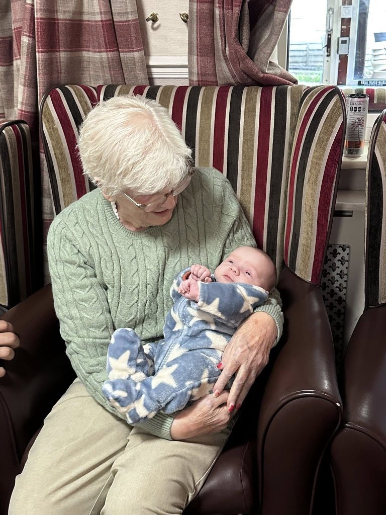 Older woman looking down at infant resting in her arms