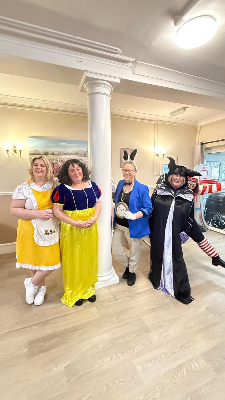Group of staff in colorful costumes posing indoors