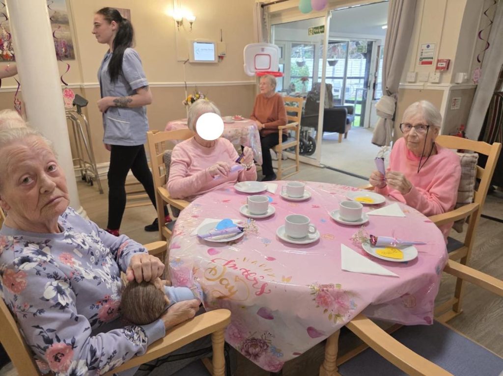 Elderly women holding small gifts at a tea gathering