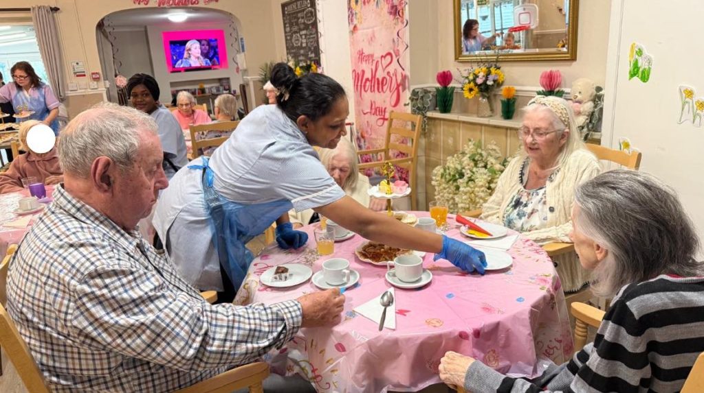 Care home tea party with staff serving drinks and snacks