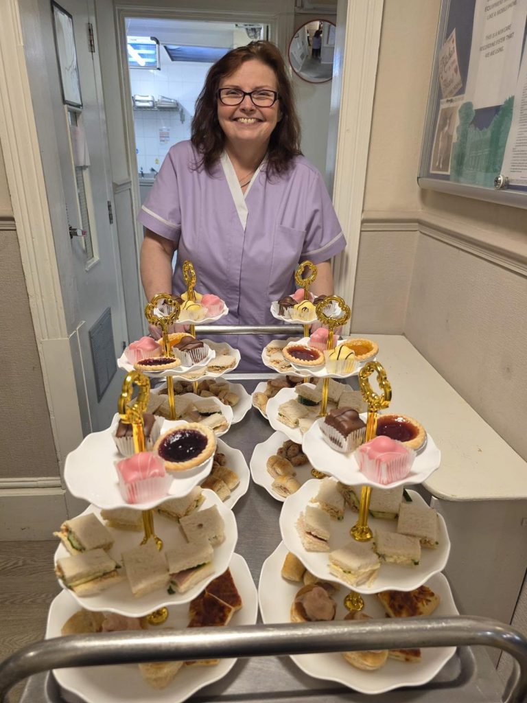 Smiling staff holding cart with sandwiches and sweets