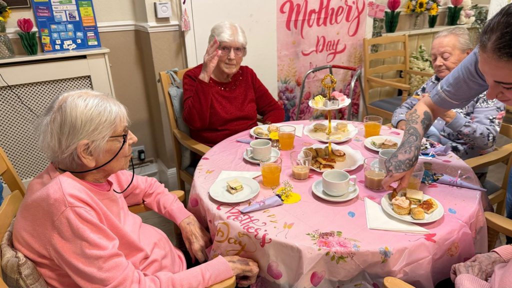 Caregiver helping serve food at tea table
