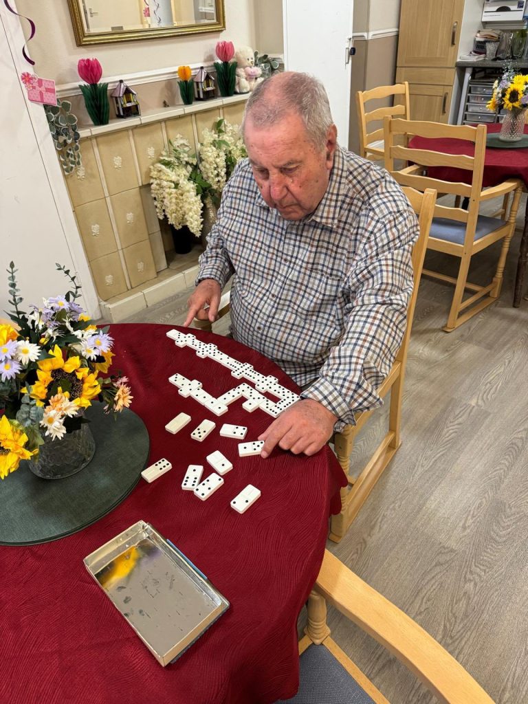 Resident concentrating while playing dominoes at a table.