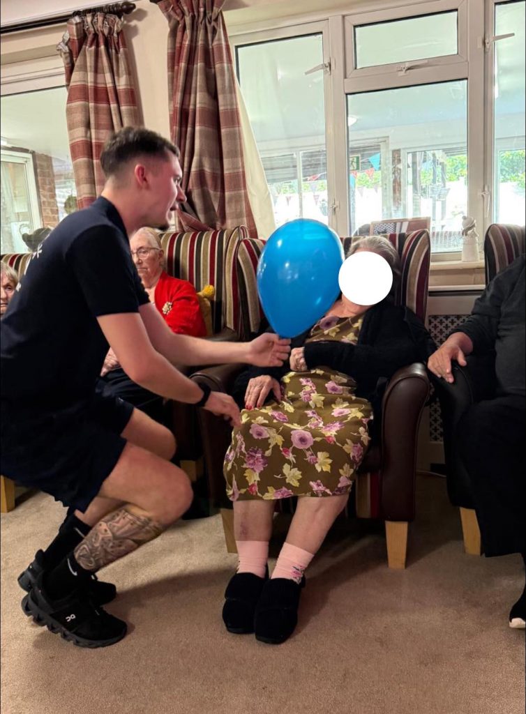 Young man engaging with elderly residents in a sitting room