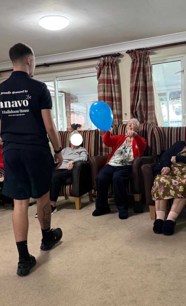 Residents and staff participating in a balloon activity in a care home lounge