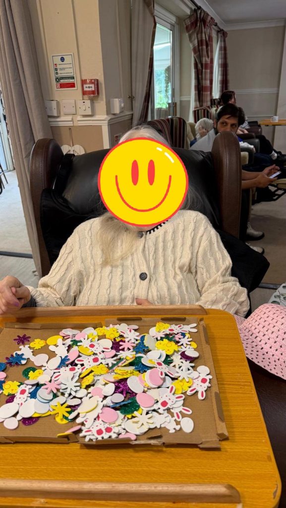 Person seated with a tray of colorful Easter craft shapes and a pink hat nearby.