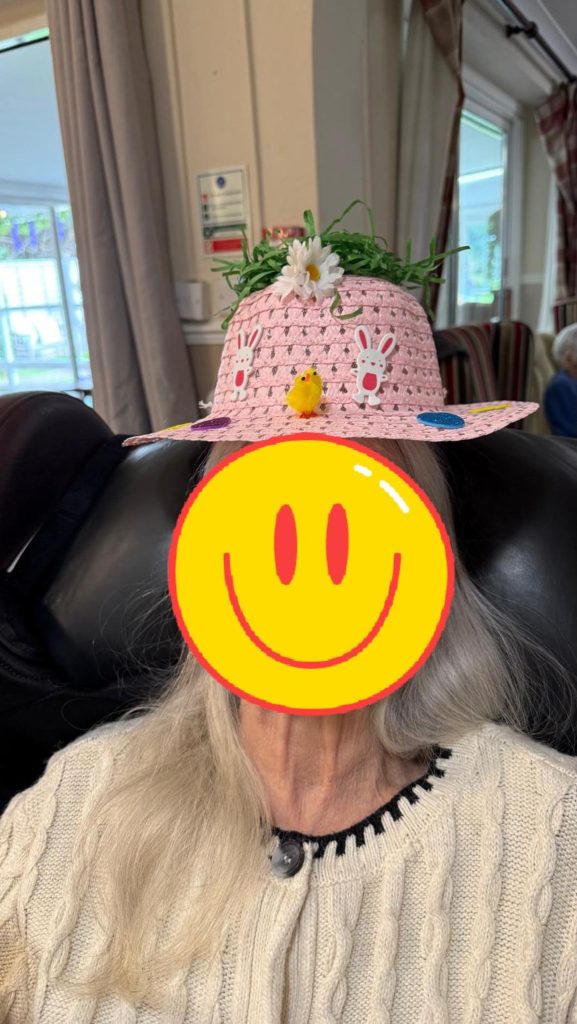 Person wearing a pink Easter hat decorated with bunnies, flowers, and a small chick.
