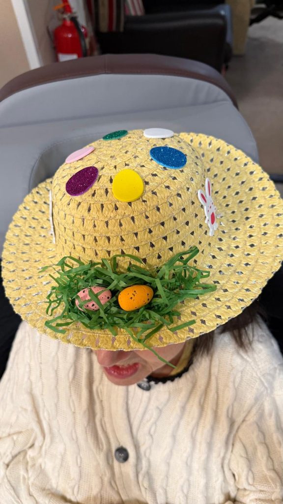 Yellow straw hat decorated with colorful eggs and faux grass nest.
