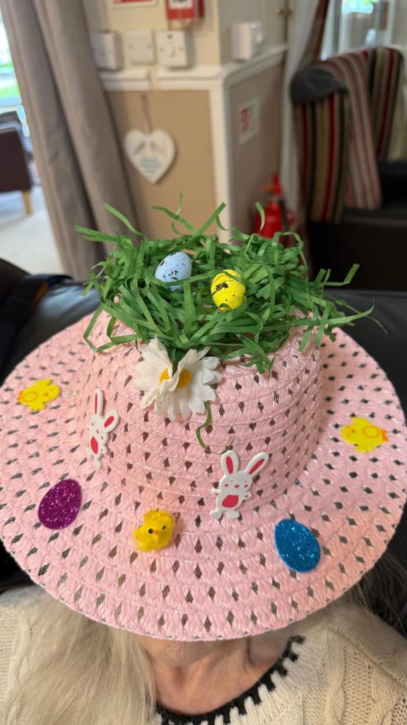 Pink Easter hat with grass nest, small eggs, daisies, and bunny decorations.