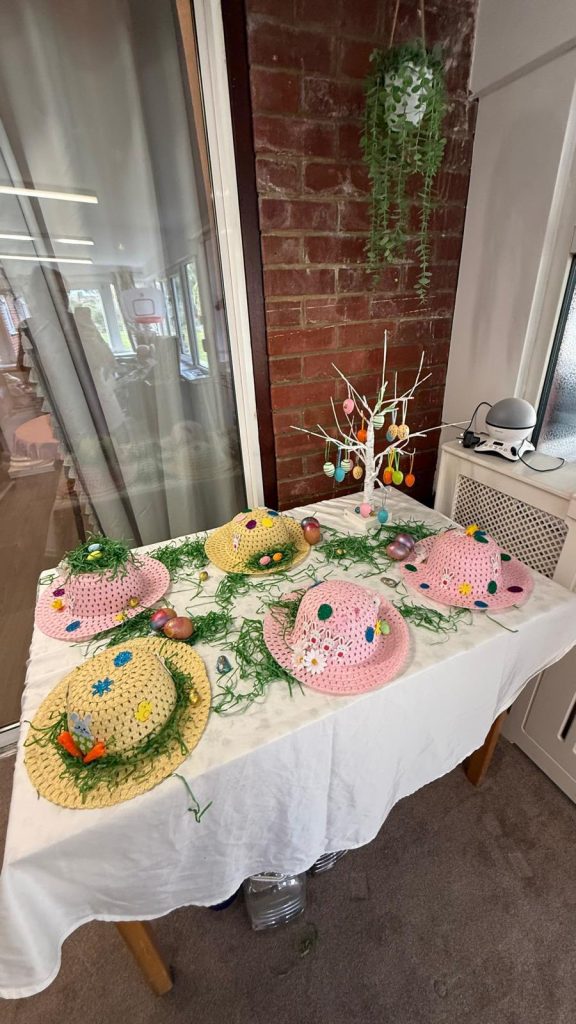 Table display of decorated Easter hats with eggs and festive decorations.