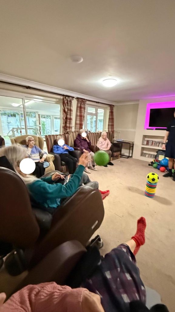 Group of elderly residents tossing a ball during a seated activity session.