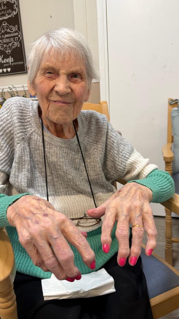 Smiling elderly woman showing her bright pink painted nails.
