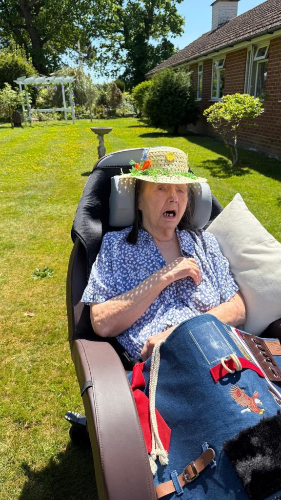 Resident relaxing in a garden chair, enjoying warm weather and fresh air.