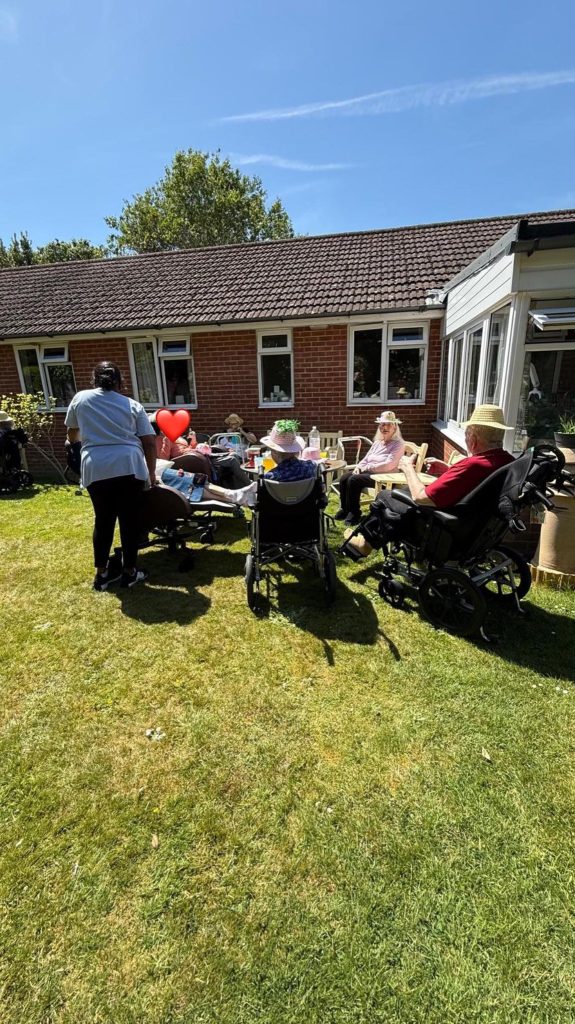 Care home residents and a staff member enjoying a sunny afternoon activity in the garden.