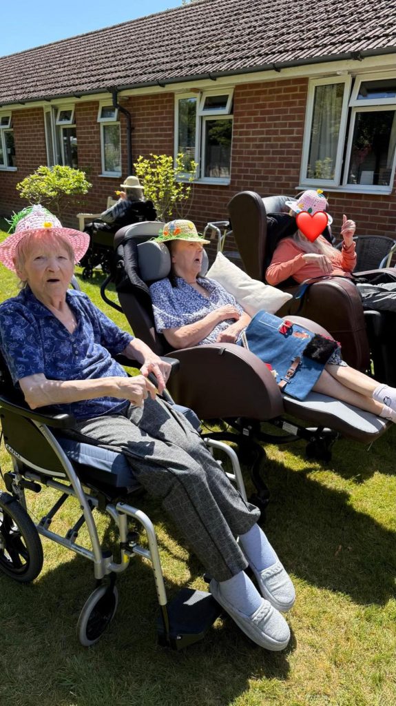 Residents wearing decorated hats and enjoying time together in the garden.