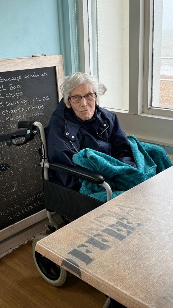 Resident relaxing indoors at a seaside café during a day trip.