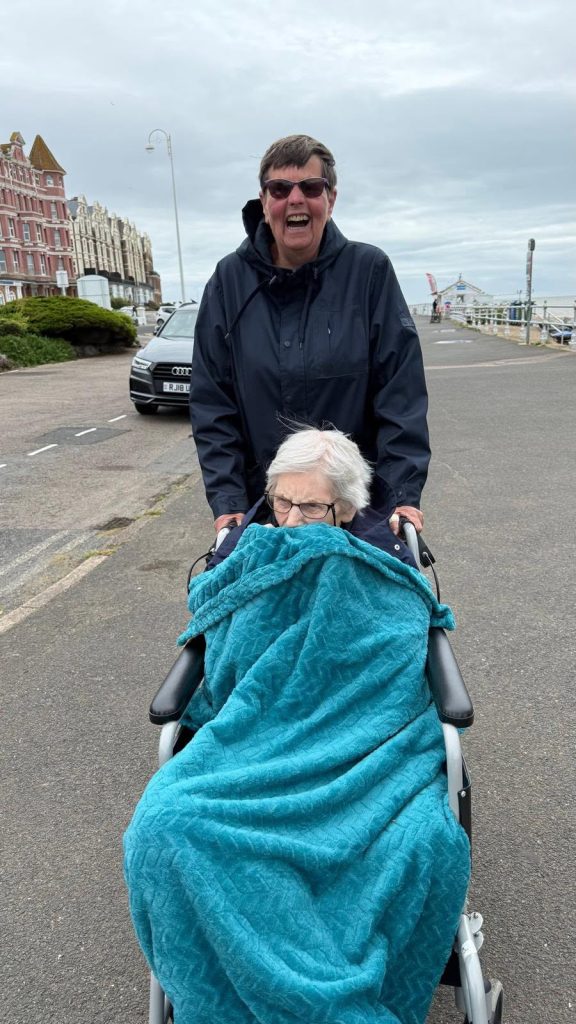Resident enjoying a seaside promenade outing with support from a companion.