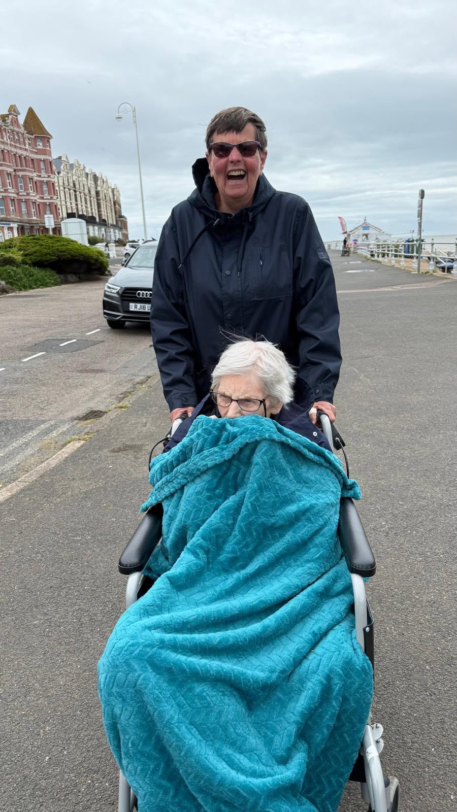 Resident enjoying a seaside promenade outing with support from a companion.