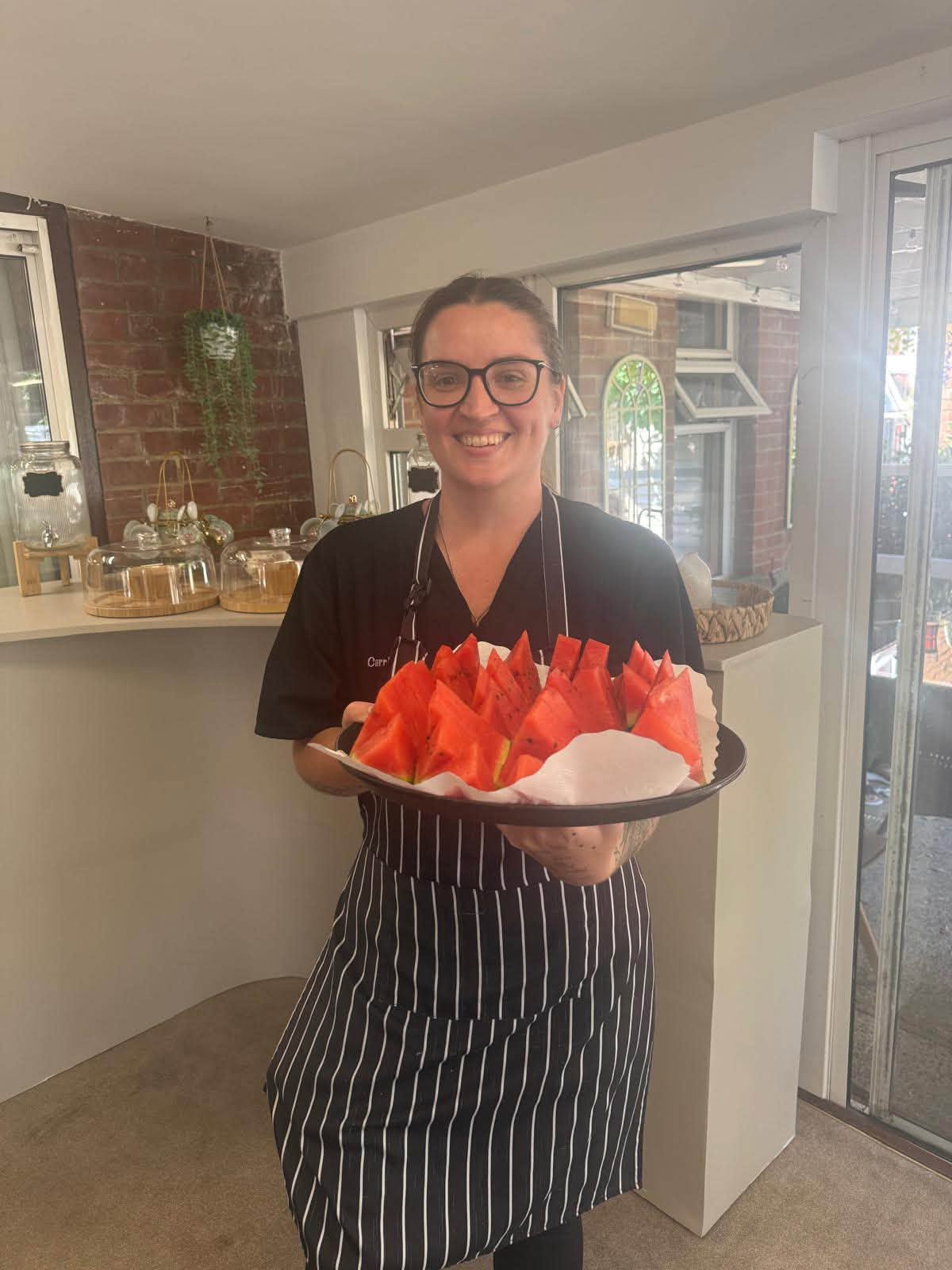 Care staff member serving fresh watermelon to residents at Orchard House Nursing Home on a warm summer day.