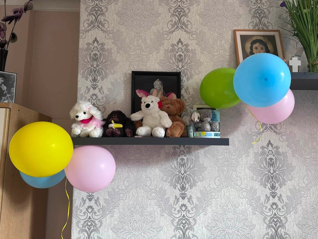 Colourful balloons and soft toys decorating a room for a birthday celebration.