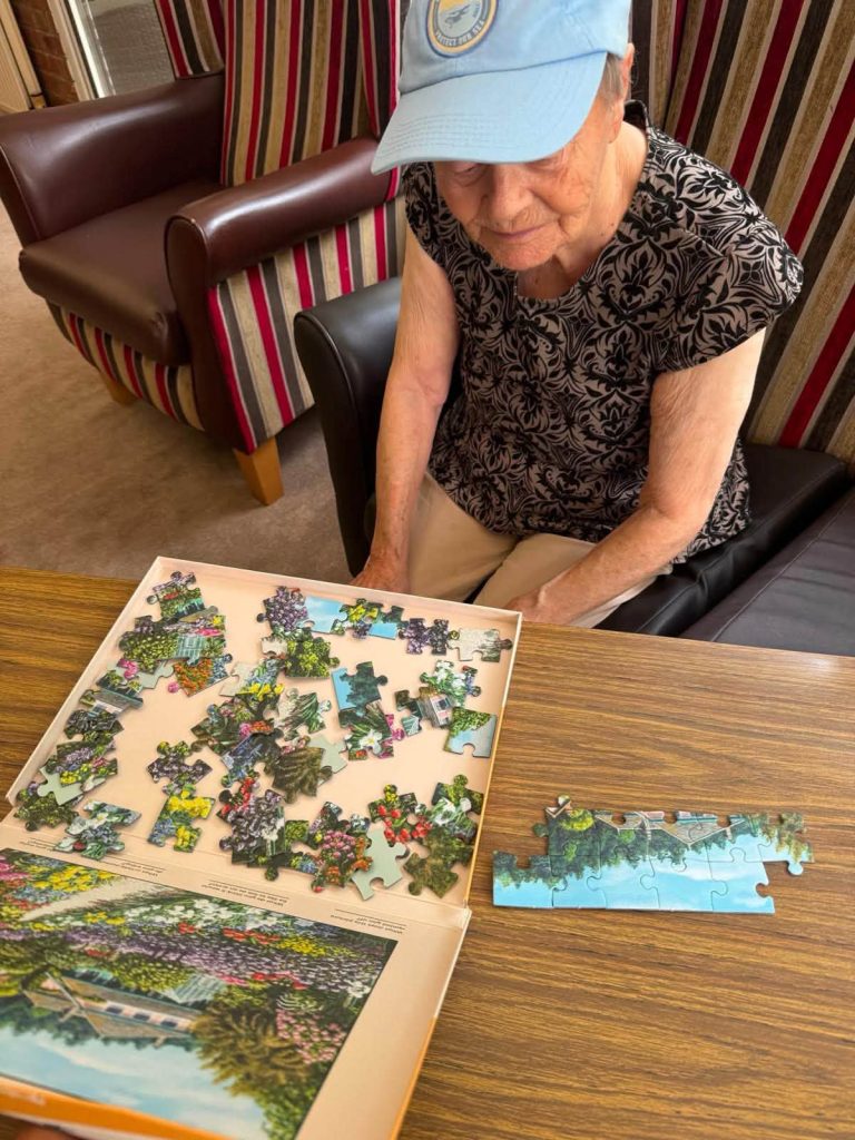 Resident concentrating on completing a colorful garden jigsaw puzzle at a table.