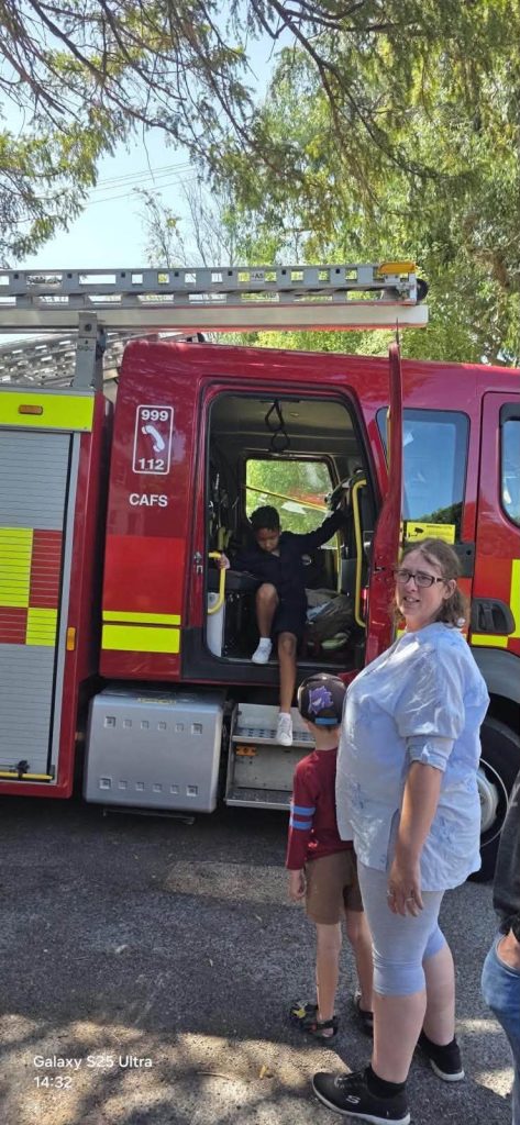 Child stepping down from a fire engine while others wait nearby.