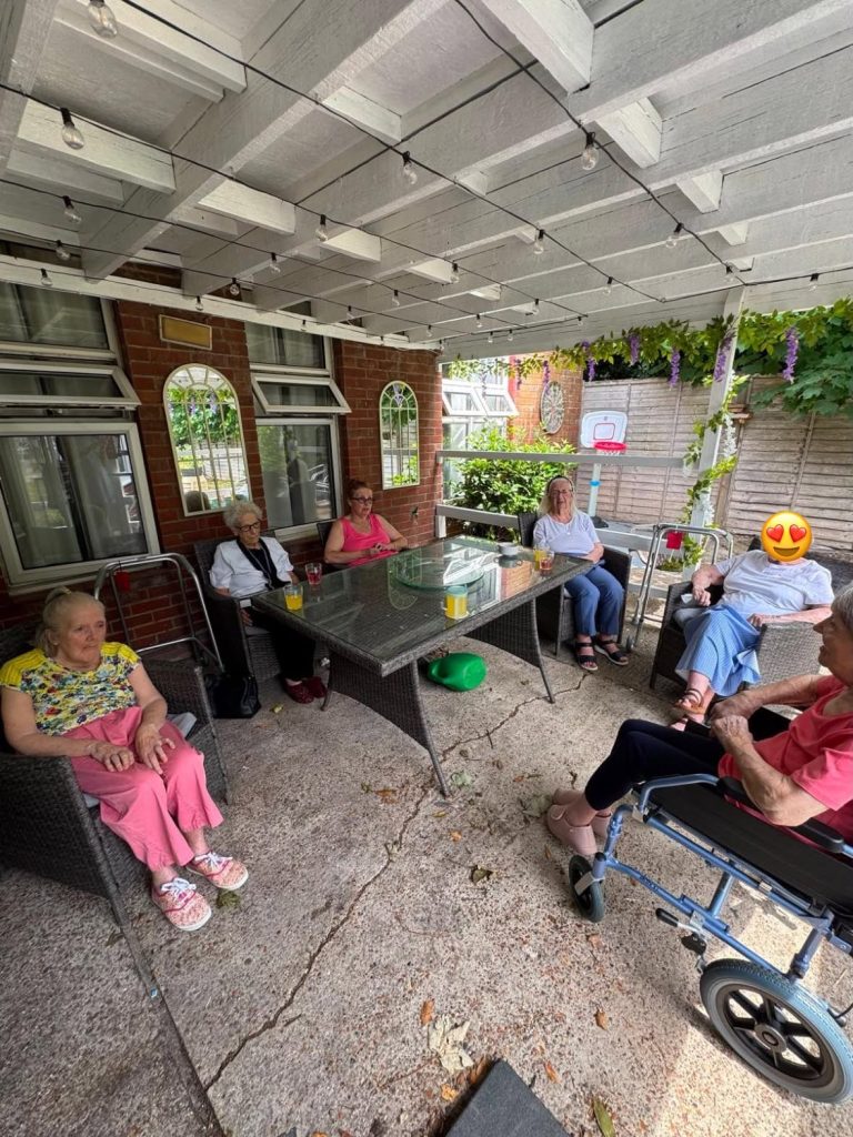 Care home residents socialising together in the outdoor seating area.