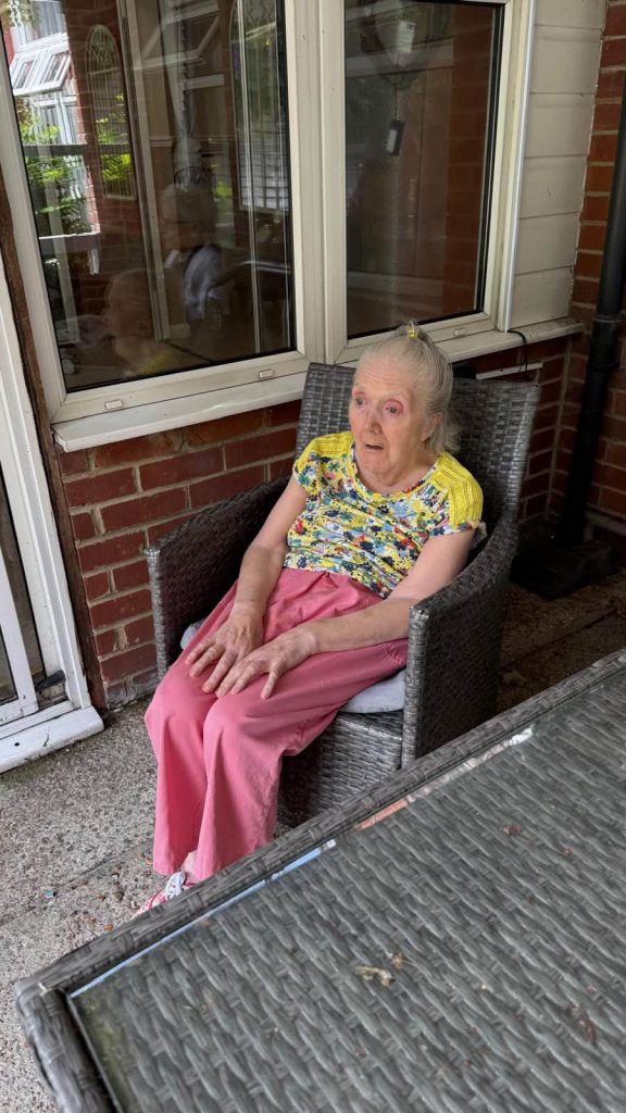 Resident sitting comfortably on the patio during a sunny afternoon.
