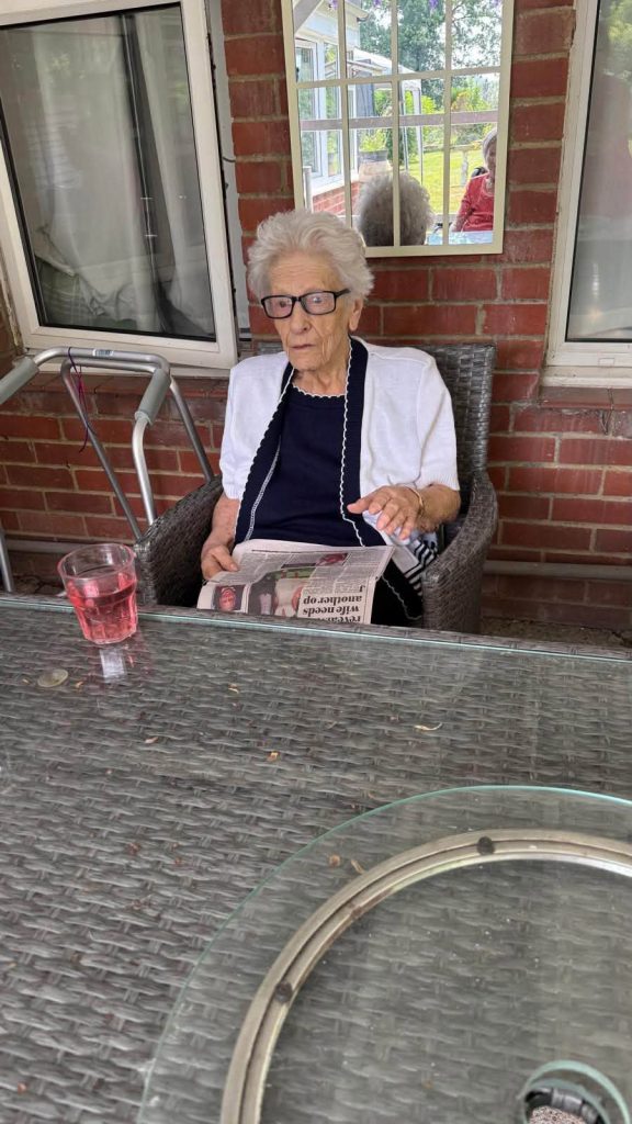 Resident reading a newspaper while relaxing on the outdoor patio.