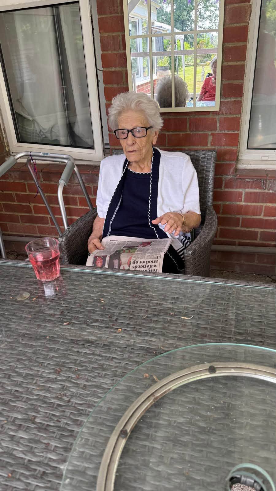 Resident reading a newspaper while relaxing on the outdoor patio.