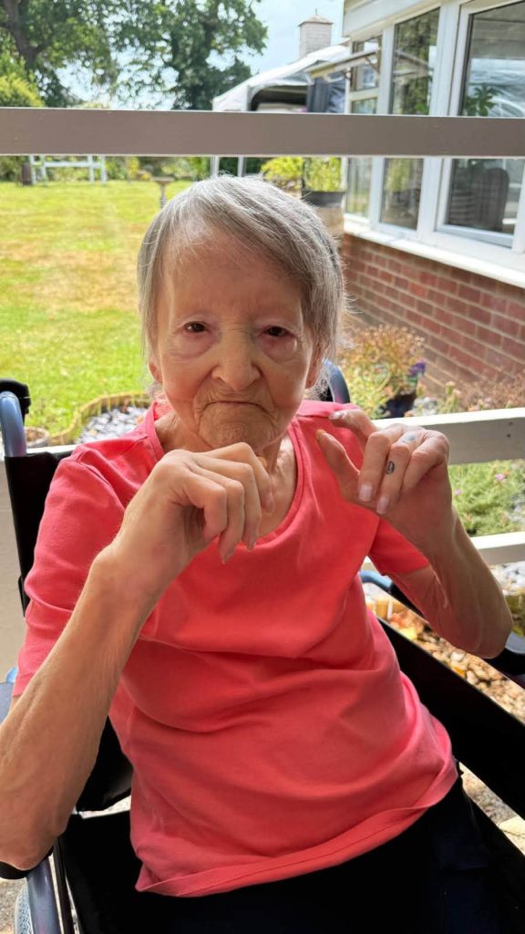 Smiling resident enjoying time outdoors in the care home garden.