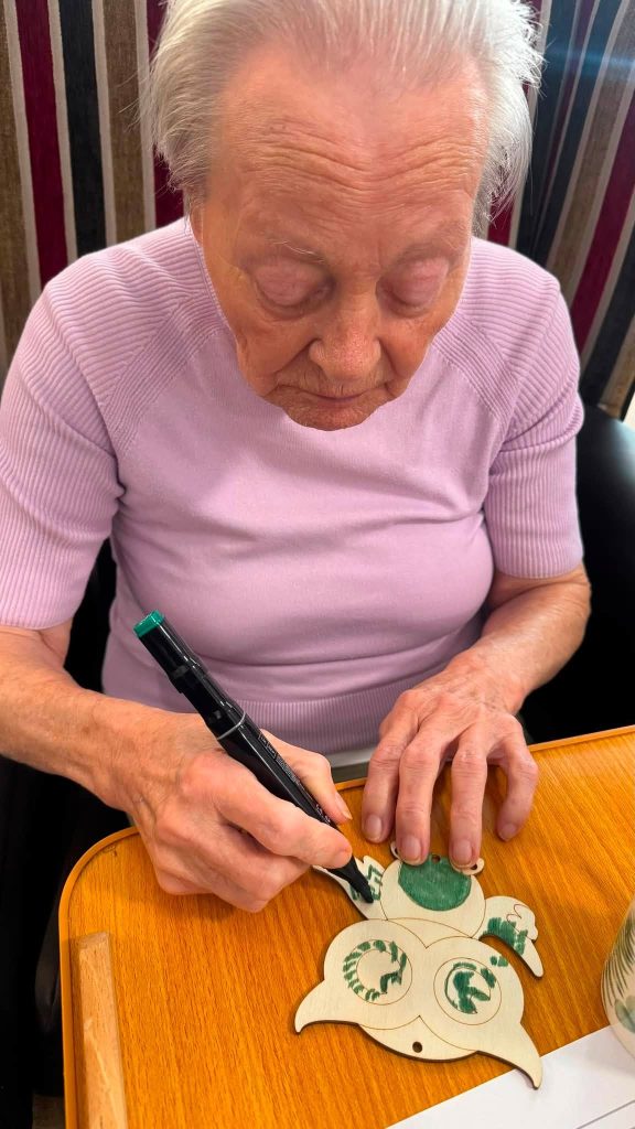 Elderly woman colouring an owl craft.