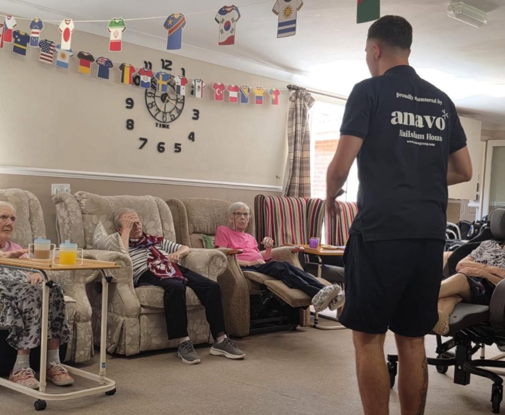 Caregiver leads a group activity with residents in a lounge.