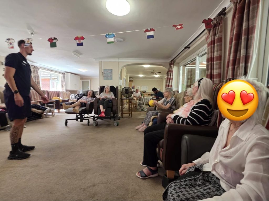 Four older women participate in a playful paper-hat activity.