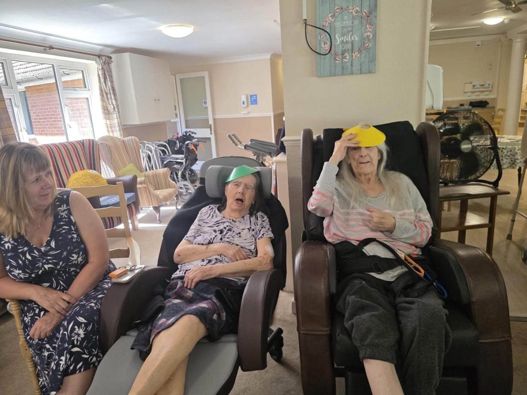 Caregiver interacts with older residents during a seated ball game.