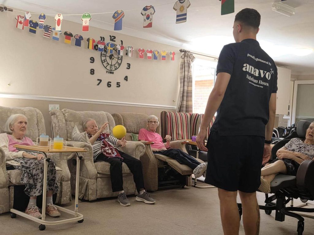Caregiver leads a seated group activity with residents.