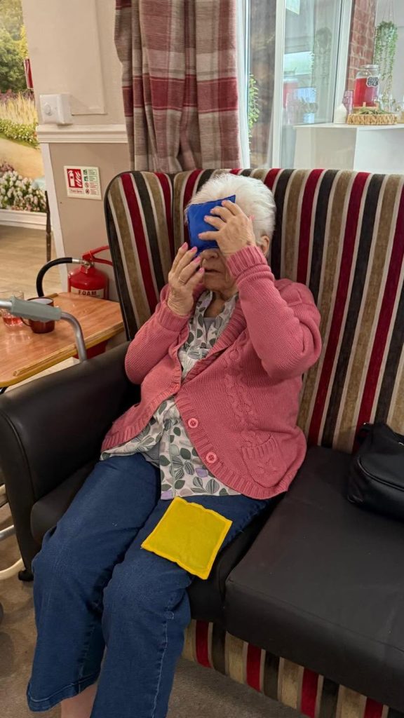 Elderly woman participating in a seated ring exercise.