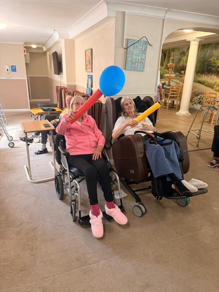 Group of elderly residents participating in a seated ball game.