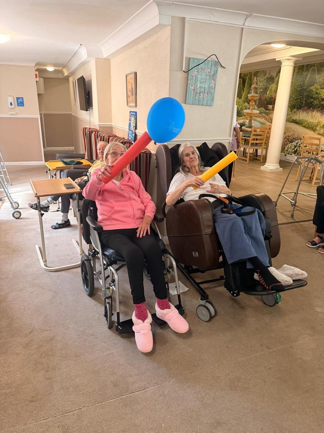 Group of elderly residents participating in a seated ball game.