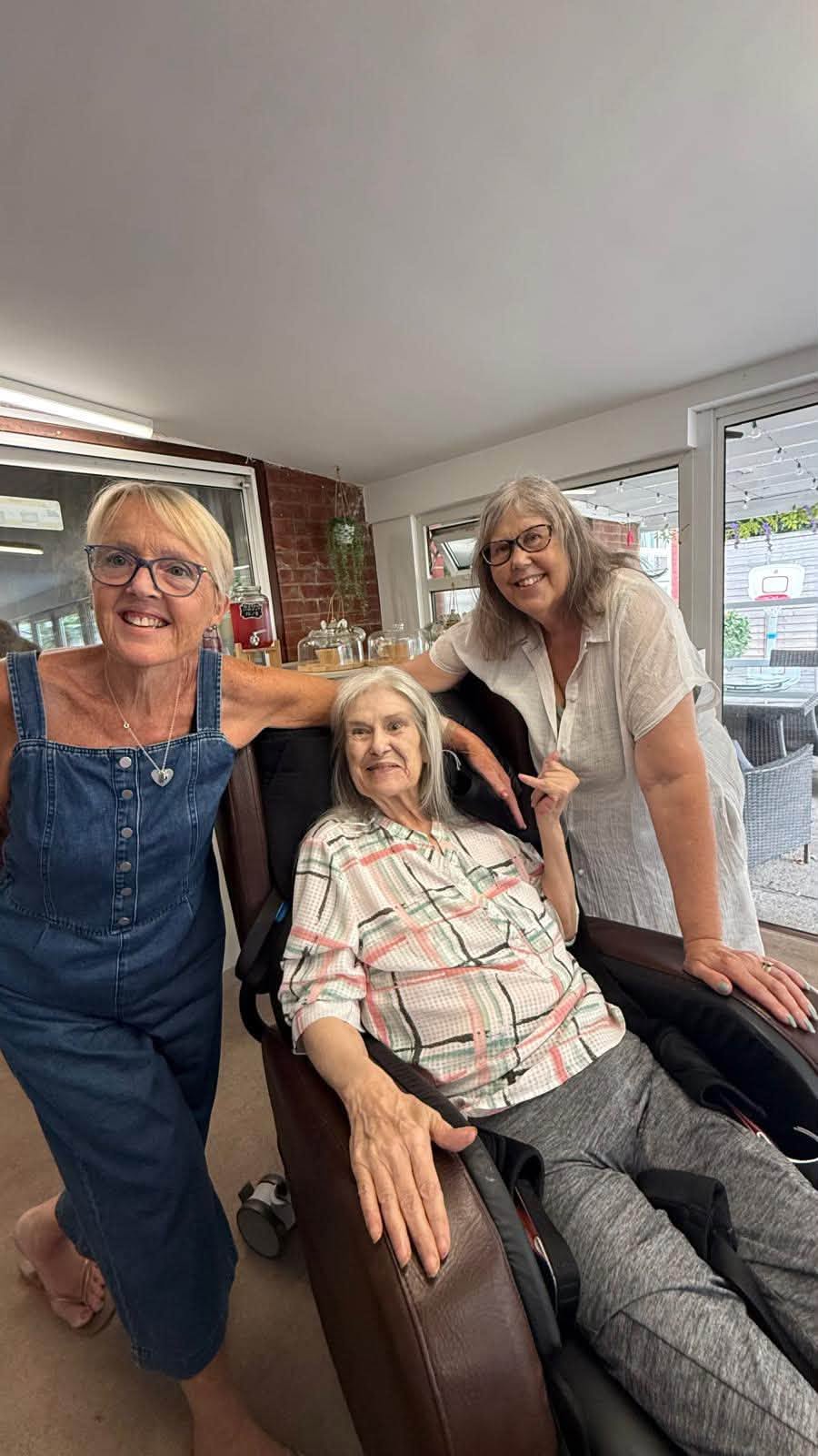 Three women smile for a photo in a cozy indoor setting.