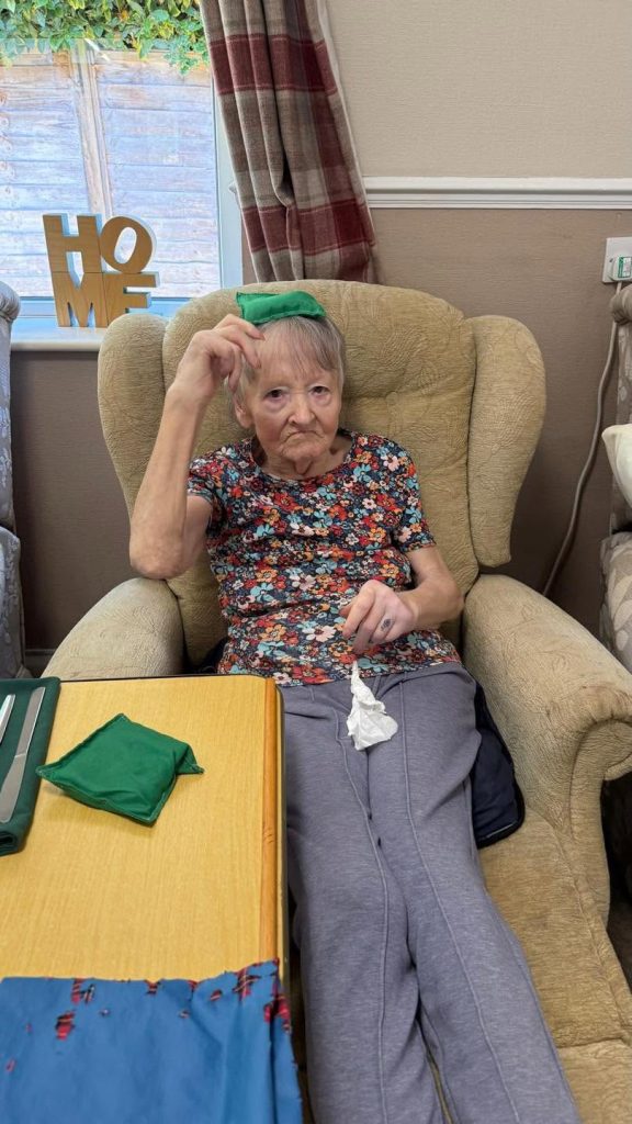 Elderly woman sitting in an armchair during a recreational activity.