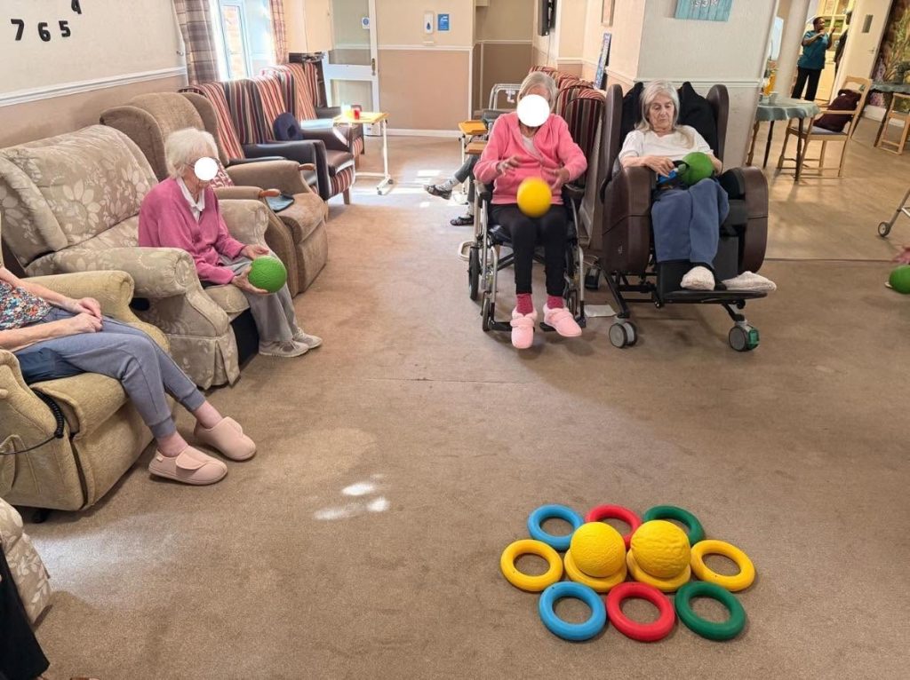 Elderly women playing with foam bats and a blue ball.