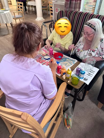 Residents taking part in a colourful painting activity with a care worker.