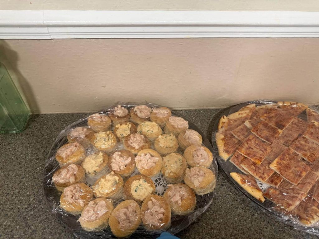 Homemade savoury snacks and sliced pizza prepared for a care home celebration.