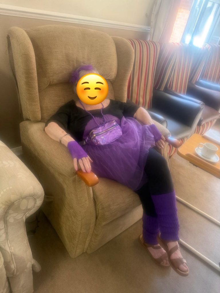 Resident enjoying the 1980s-themed celebration in a purple fancy-dress outfit.