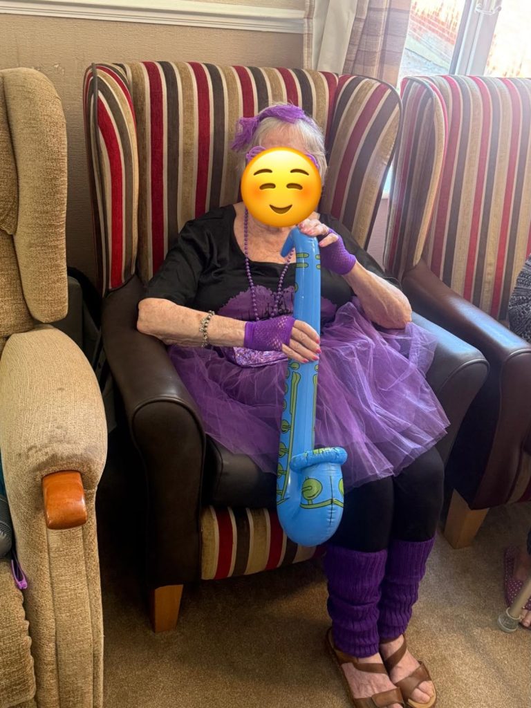 Resident enjoying the themed party while holding an inflatable red guitar.